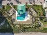 Aerial view of the expansive oceanfront pool deck featuring a swimming pool, spa, abundant lounge seating, and direct beach access.