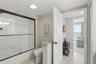 Convenient Jack-and-Jill bathroom featuring a tub/shower combination with glass enclosure, neutral tile flooring, and access from adjoining rooms.