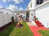 Enclosed backyard featuring a covered patio, paved hardscaping, a manicured lawn, and perimeter vinyl fencing