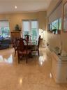 Polished stone flooring, crown molding, and glass-paned double doors with integrated shades
