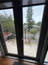 Double glass door entry to a private balcony featuring a wrought iron railing and wood-finish flooring
