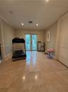 Neutral-toned interior space featuring polished stone flooring, crown molding, recessed lighting, and double glass-paned doors