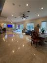 Open-concept interior featuring large-format stone tile flooring, recessed lighting, ceiling fan, and multiple glass-paned doors
