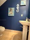 Pedestal sink with a polished chrome faucet, stone-finish floor tiling, and neutral wall base trim