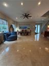 Large-format natural stone flooring, recessed ceiling lighting, a multi-blade ceiling fan, and a staircase featuring decorative metal balusters