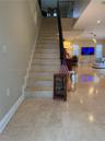 Staircase featuring stone-finish treads, decorative metal railings, and polished stone tile flooring