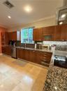 Kitchen featuring wooden cabinetry, stone-surface countertops, stone tile flooring, integrated double oven, and stainless steel dishwasher