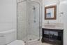 Corner shower enclosure with glass panels, stone-tiled walls, and a handheld showerhead