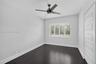 Room featuring wood-finish flooring, plantation shutters, and a four-blade ceiling fan
