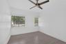 Room featuring wood-finish flooring, a matte-finish ceiling fan, and horizontal window blinds