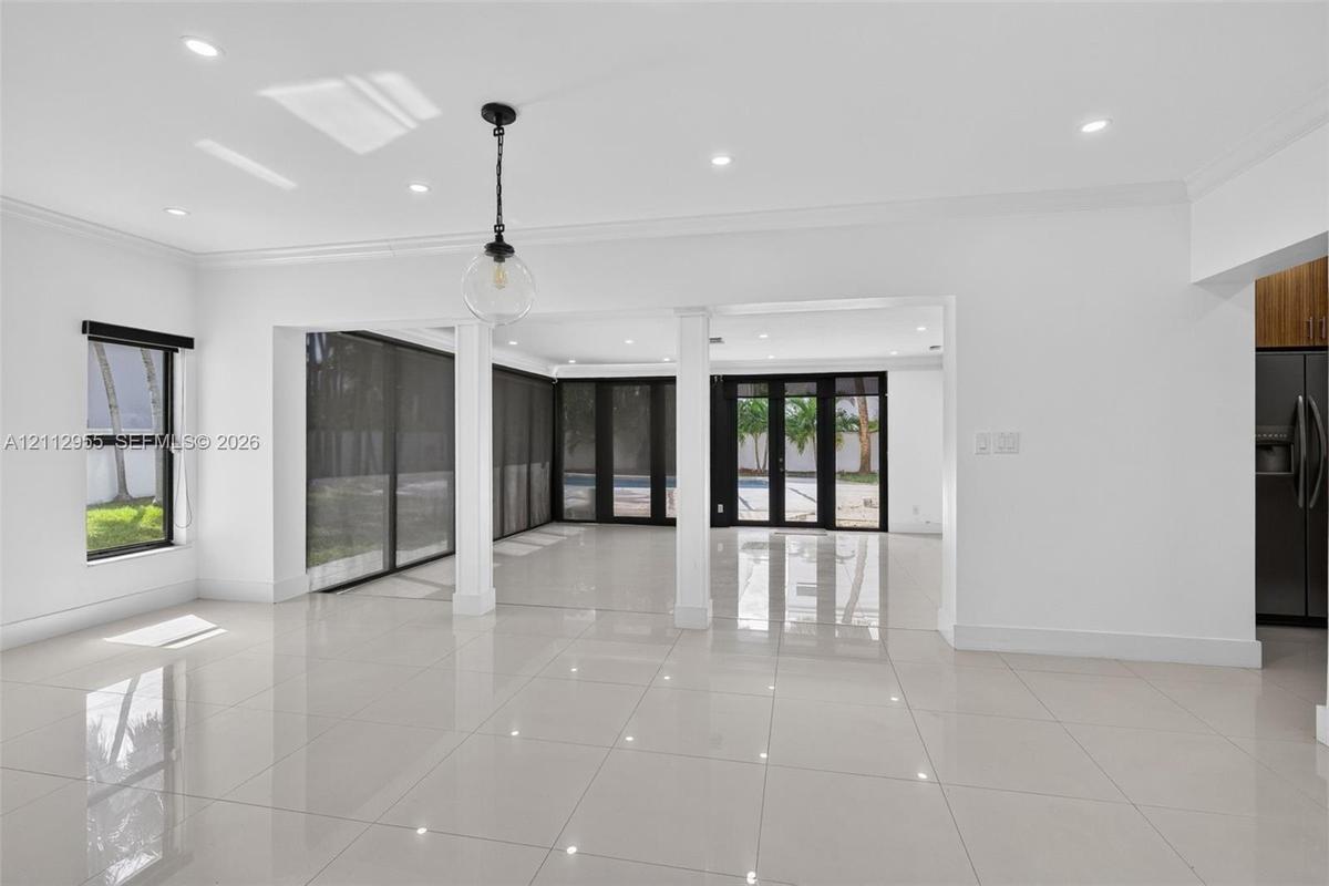 Large-format polished tile flooring, recessed ceiling lighting, structural support columns, black-framed sliding glass doors, and a decorative globe p