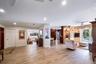 Open-concept interior featuring light wood-finish flooring, recessed lighting, built-in light wood cabinetry, and double glass doors providing exterio