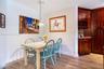 Wood-finish flooring, cherry-toned cabinetry with built-in wine storage, stone-surfaced countertop, and a contemporary glass pendant light fixture