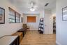 Room featuring wood-finish flooring, dual windows with horizontal blinds, a ceiling fan with integrated lighting, and a reach-in pantry