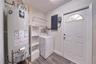 Utility area featuring wood-finish flooring, a white metal exterior door with a semi-circular transom window, and white built-in shelving