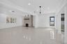Open-concept interior featuring light-toned tile flooring, a floor-to-ceiling stacked stone fireplace with a wood mantel, recessed lighting, and a mod