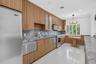 Kitchen featuring wood-grain cabinetry, stone countertops with matching backsplash, stainless steel appliances, polished tile flooring, and a built-in