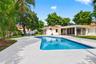 Backyard featuring an in-ground swimming pool, expansive concrete patio, screened-in lanai, and mature landscaping