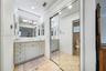 Vanity featuring a stone-surface countertop, integrated undermount sink, multi-drawer cabinetry, and a large wall-mounted mirror