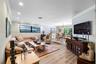 Open-concept interior featuring recessed lighting, crown molding, wood-finish flooring, and a raised platform area with glass-paned double doors