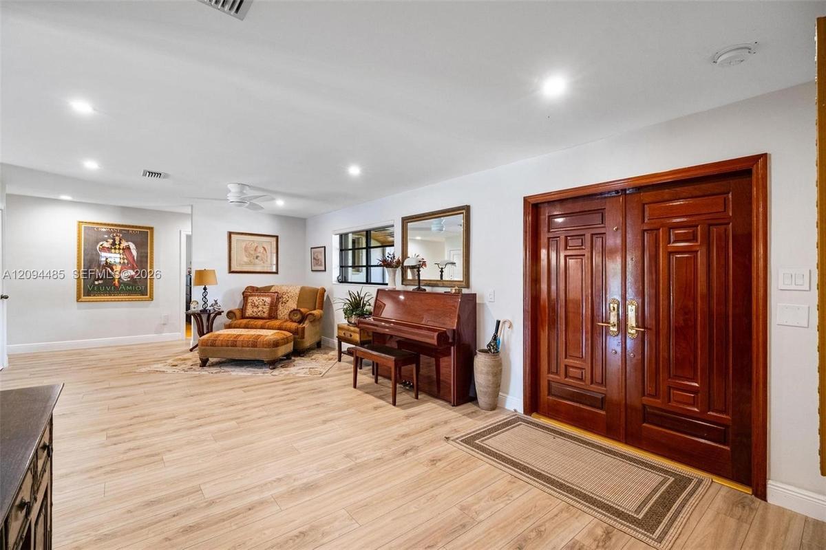 Double-entry front doors with polished wood finish, wood-finish flooring, and recessed ceiling lighting