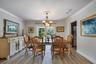 Dining space featuring wood-finish flooring, crown molding, a central multi-light chandelier with a ceiling medallion, and glass-paneled French doors