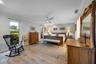 Room featuring wood-finish flooring, a modern three-blade ceiling fan, crown molding, and dual windows with roller shades