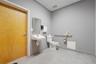 Wall-mounted sink, flat-panel wood-finish door, tile flooring, and metallic grab bars