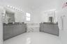 Dual vanities featuring gloss-finish cabinetry, stone countertops, integrated basins, and polished hardware, complemented by a tiled soaking tub and p