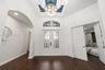 Foyer featuring double entry doors with decorative glass inserts, a recessed tray ceiling with accent color, a crystal chandelier, arched architectura