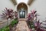 Arched entryway featuring a paver walkway, double-door entry with arched transom window, built-in geometric lantern-style lighting, and mature landsca