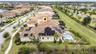Aerial perspective featuring a tile-roof residence with integrated solar panel arrays, a screened-in swimming pool, and an expansive lawn