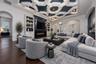 Virtually staged. Living area featuring an intricate geometric coffered ceiling, linear fireplace with a shiplap surround, built-in shelving, hardwood