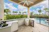 Covered outdoor kitchen featuring light-toned cabinetry, solid surface countertops, stainless steel refrigeration, and a sink, complete with stone-til