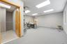 Interior workspace featuring recessed ceiling lighting, wall-to-wall carpeting, built-in shelving, and a secondary room finished with tile flooring
