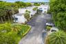 Multi-story commercial building featuring a dedicated asphalt parking lot, manicured lawn areas, established palm trees, and perimeter landscaping