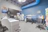 Industrial-style workspace featuring exposed ceiling joists, blue exposed ductwork, concrete flooring, and horizontal slat wall paneling