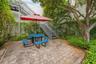 Paver patio area featuring mature trees, lush greenery, and a metal exterior staircase