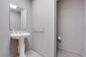 White pedestal sink featuring a metallic faucet, framed wall-mounted mirror, and horizontal towel bar finished in coordinating metallic hardware, set 