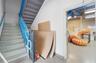 Interior stairwell featuring painted metal stairs, blue steel handrails, and exposed ceiling infrastructure with linear lighting
