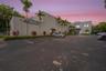 Commercial building featuring concrete exterior walls, paved asphalt parking lot, and manicured landscaping including mature palm trees