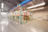 Industrial warehouse space featuring polished concrete flooring, exposed high-clearance ceilings, integrated steel pallet racking systems, and suspend
