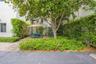 Outdoor area featuring paver hardscaping, mature trees, dense privacy hedging, and metal staircase