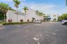 Commercial exterior featuring a concrete facade, multiple entry points, dedicated asphalt surface parking, and perimeter landscaping with mature palm 