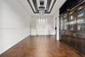Wood-finish flooring, dramatic coffered ceiling with black detailing, built-in floor-to-ceiling cabinetry with glass-panel doors, and an elongated mul