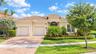 Stucco exterior featuring a multi-hipped tile roof, a two-car garage, and a paver driveway, complemented by professional landscaping