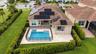 Aerial view of a residential property featuring a tiled roof equipped with integrated solar panels, a private swimming pool with a built-in spa, and a