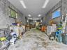 Spacious garage featuring exposed concrete block walls, high-clearance ceilings, concrete flooring, multiple horizontal-slider windows, and linear LED