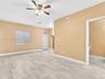 Neutral-toned interior featuring wood-finish tile flooring, a multi-blade ceiling fan with integrated light fixture, and a single-hung window with fro