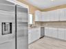 Kitchen featuring white shaker-style cabinetry, stainless steel appliances, speckled stone countertops, and wood-finish tile flooring
